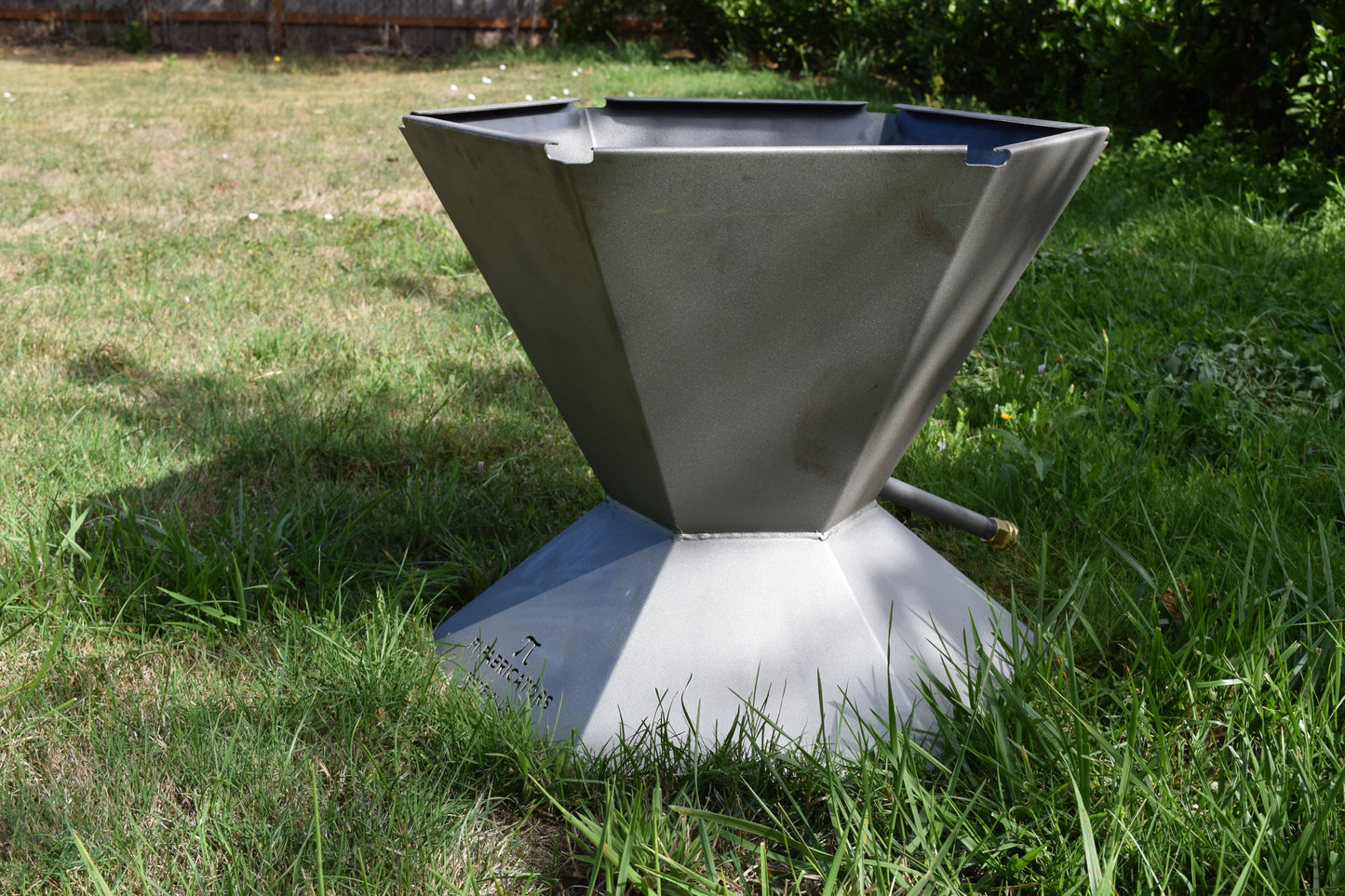 Side view of the biochar fire pit sitting on green grass.