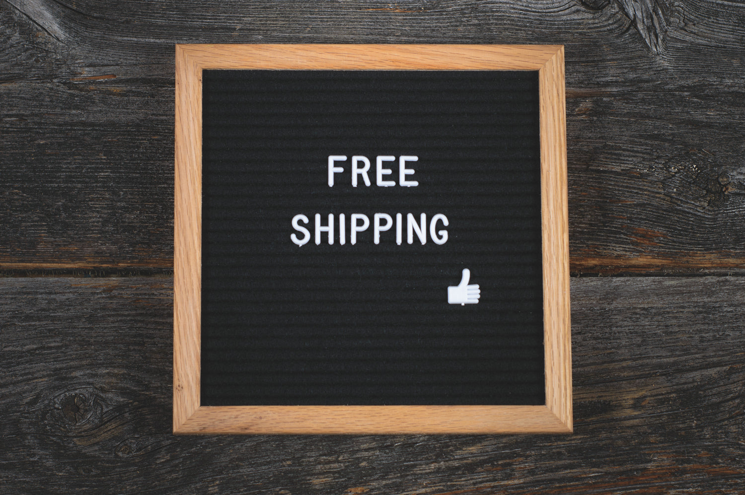 Free shipping written in white letters on a black background framed in a wooden frame.