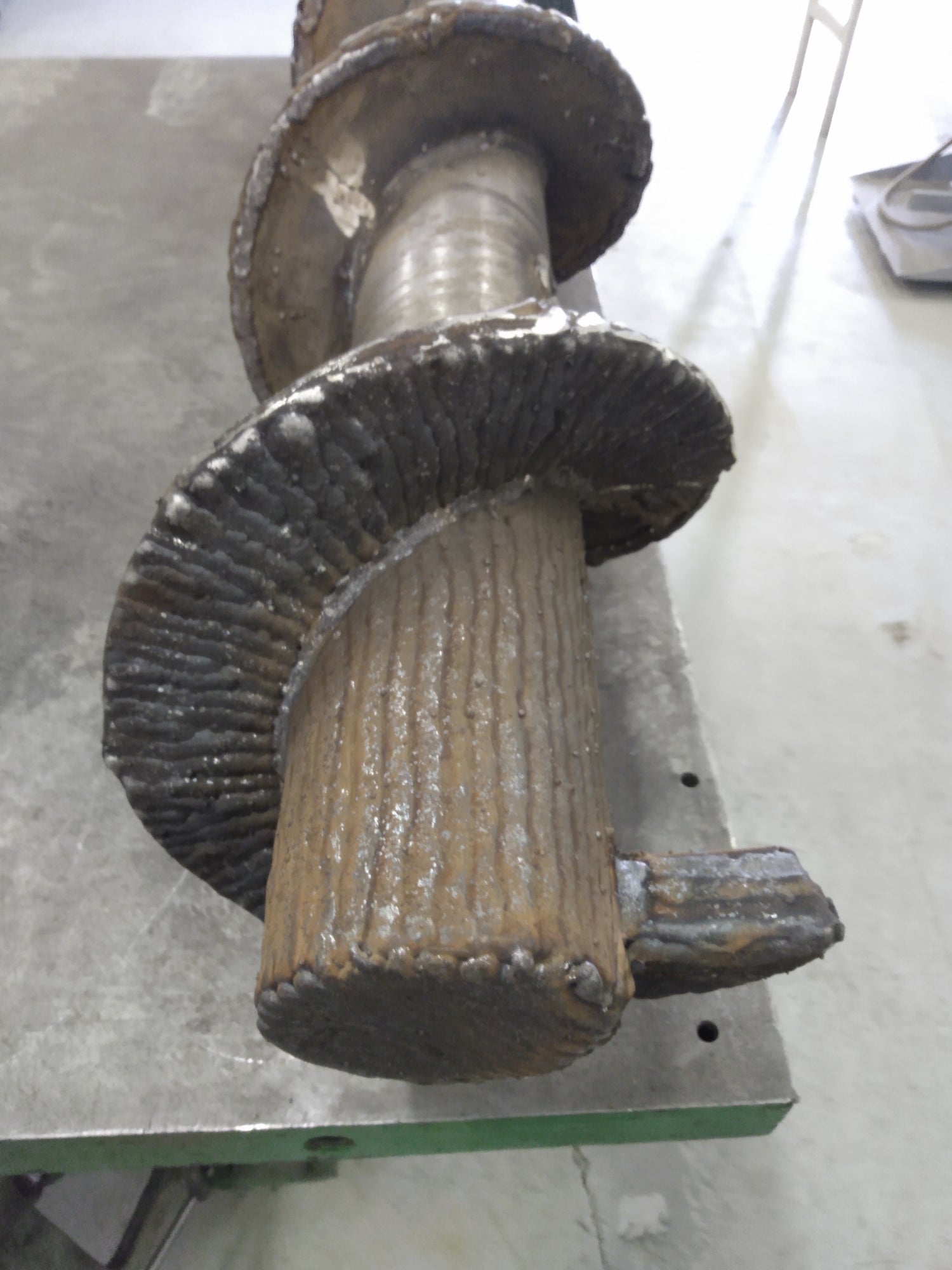 A front view of a hardfaced steel auger, designed for compacting plastic bottles for recycling.