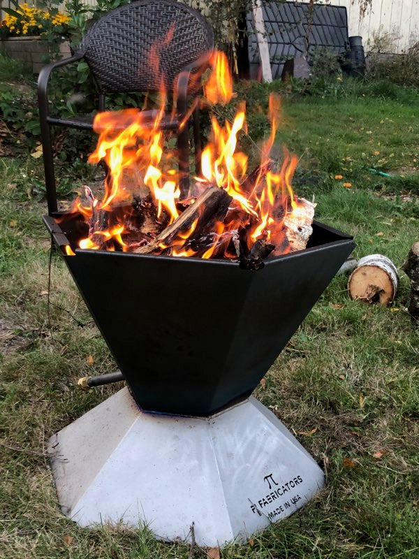 The Biochar Fire Pit with a fire burning with a chair in the background. 