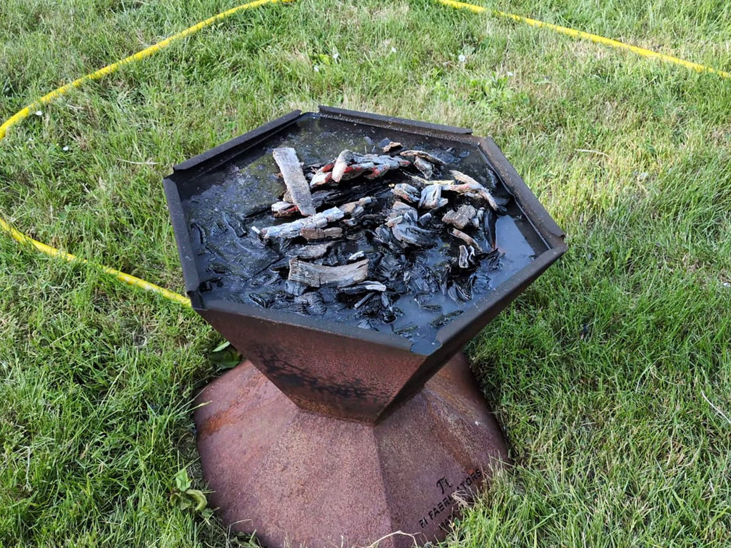 The Biochar-Making Fire Pit filled with water from the quench pipe, quenched biochar at the surface