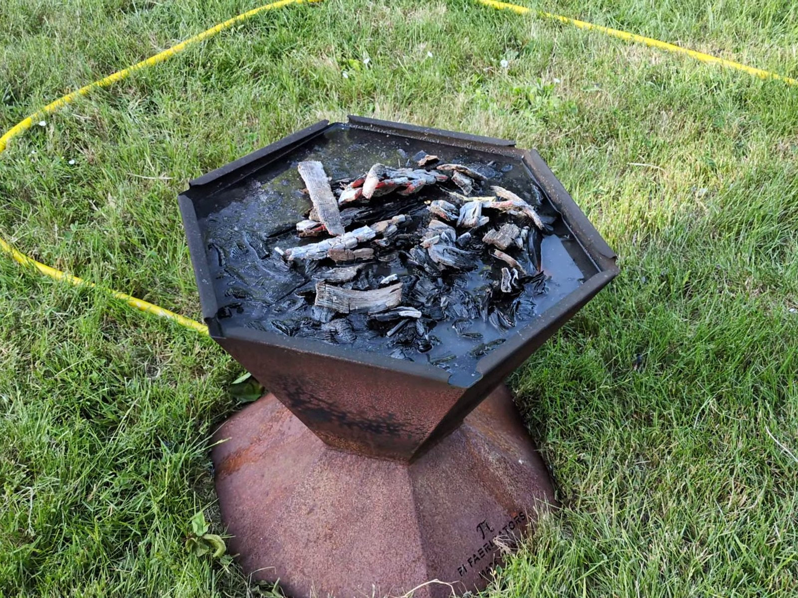 The Biochar-Making Fire Pit filled with water from the quench pipe, quenched biochar at the surface