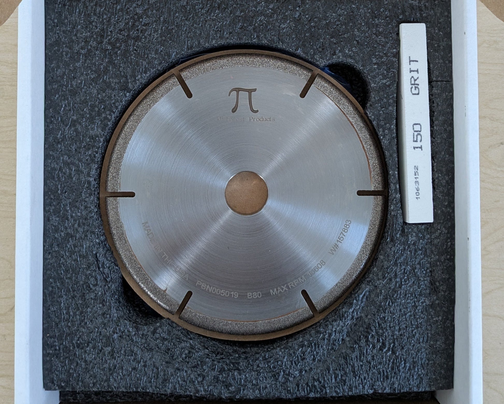 A CBN grinding wheel and a white dressing stick packaged together inside a cardboard shipping box