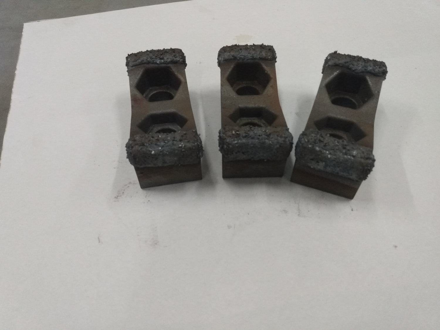 Three hammer mill hammers with a thick coating of MIG Tungsten Carbide embedding hardface.