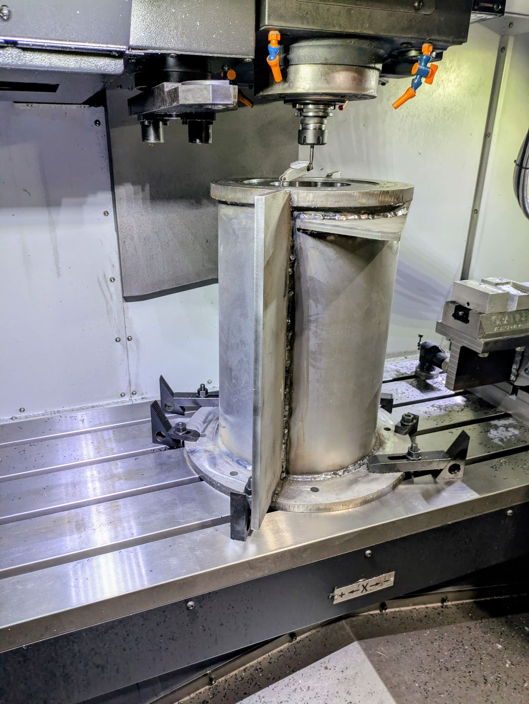 Dial indicator inspection of a large weldment on a CNC milling machine to verify precision and warpage removal.