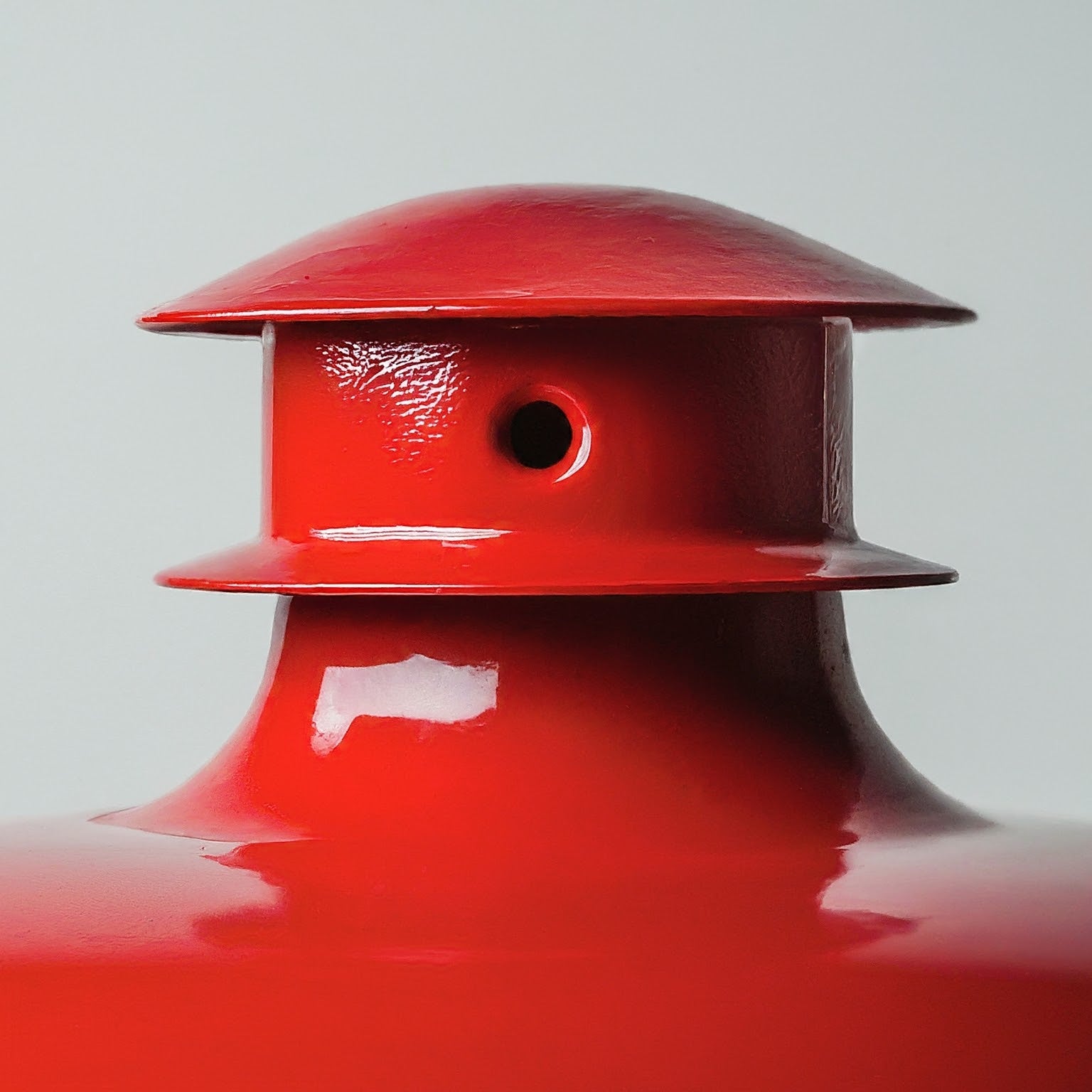 Red painted metal part on white background