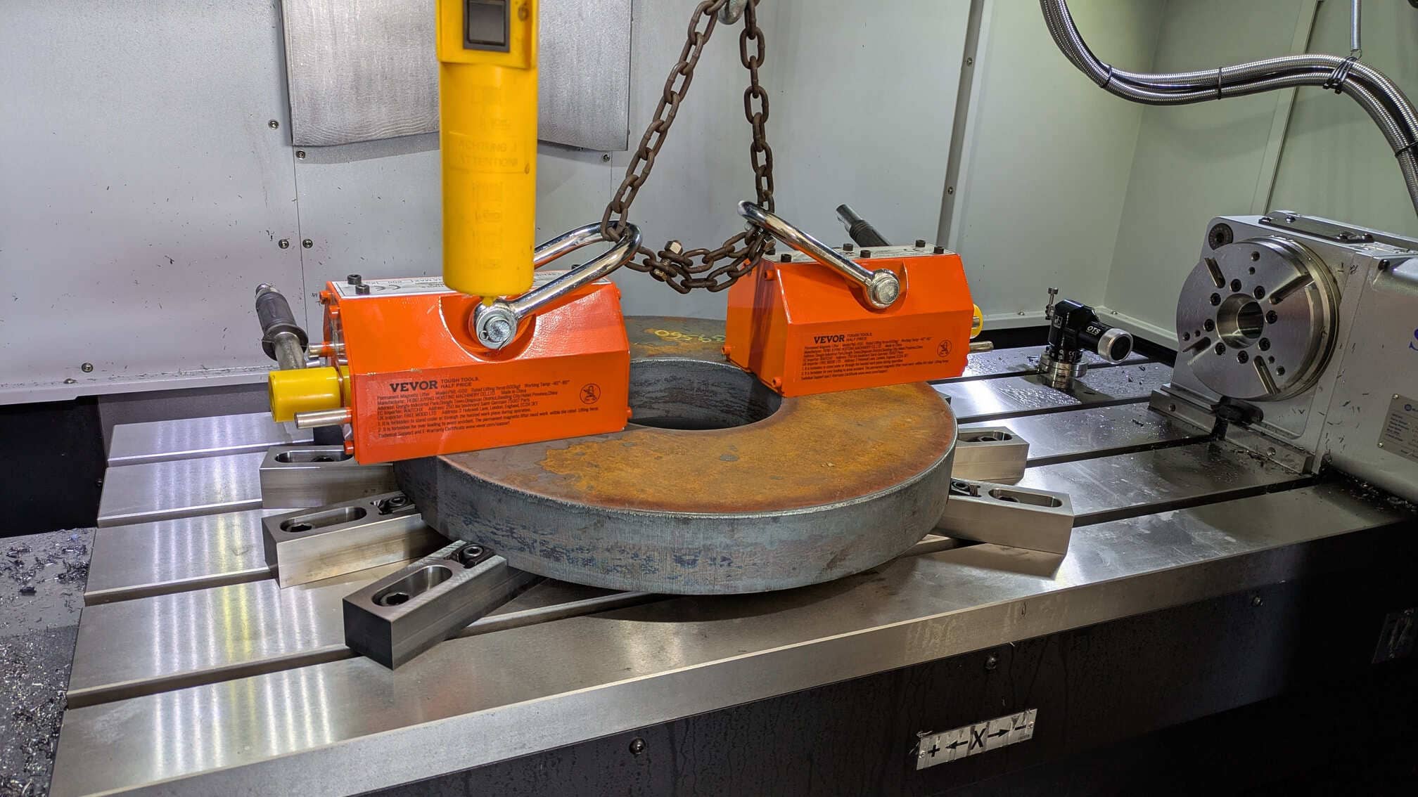 Lifting magnets placing a large, donut-shaped blank onto the CNC table to be machined into a wood products conveyor sprocket.